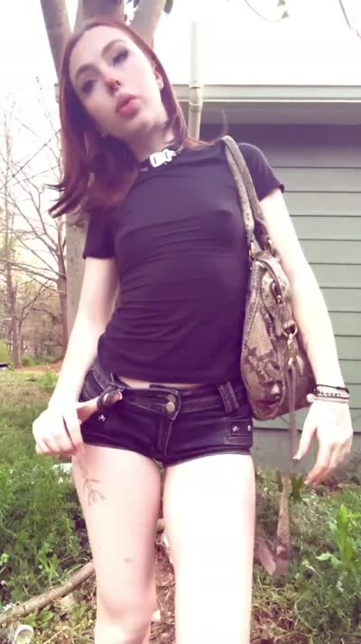 Redhead in a black tee and denim shorts outdoors