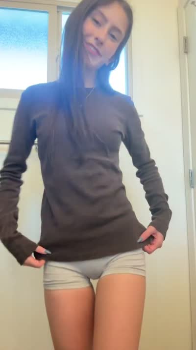 Brunette in a brown long-sleeve top and grey shorts