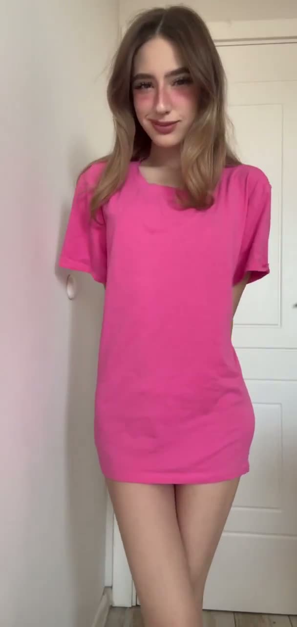 Brunette in an oversized pink tee in a doorway