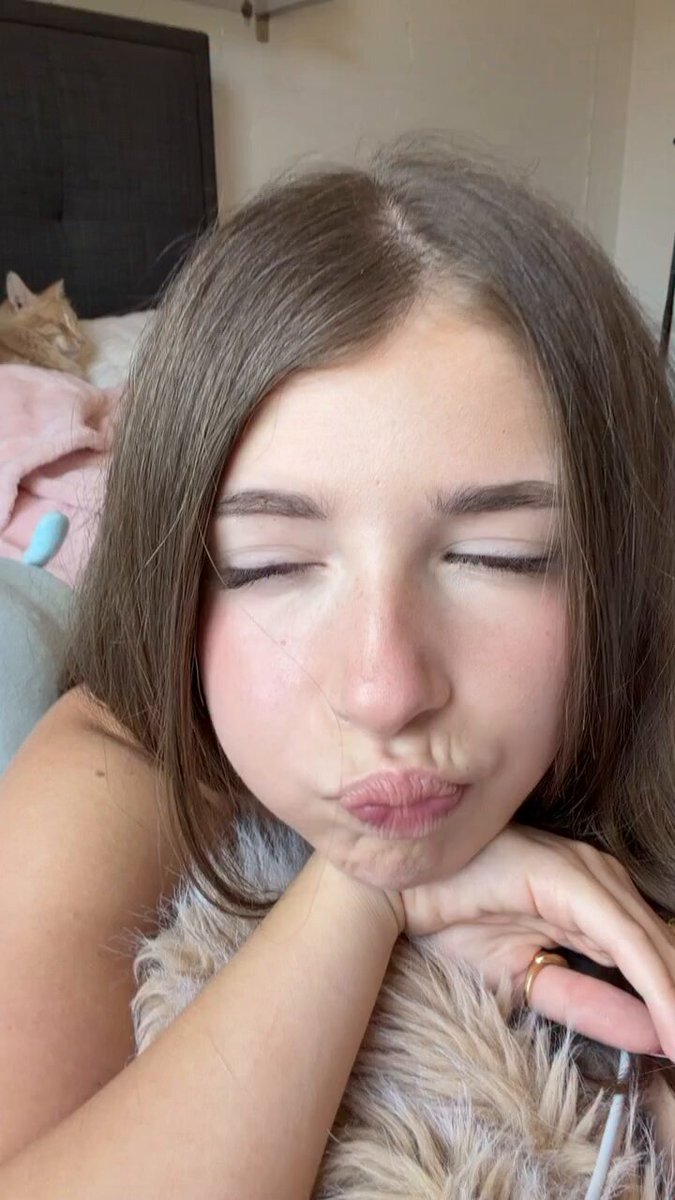 Brunette making a kissy face with a cat on the bed (@RamonahJessi)