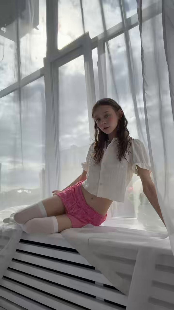 Brunette in a white blouse and pink shorts on a window seat (@somurevix)
