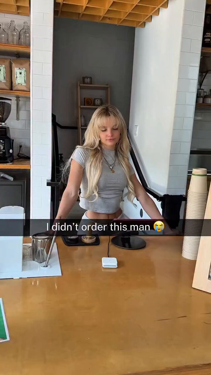 Blonde in a gray crop top behind a cafe counter (@trippiesworld)