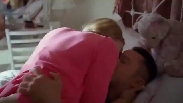 Blonde in a pink top hugging a man on a bed (@drobertson7678)