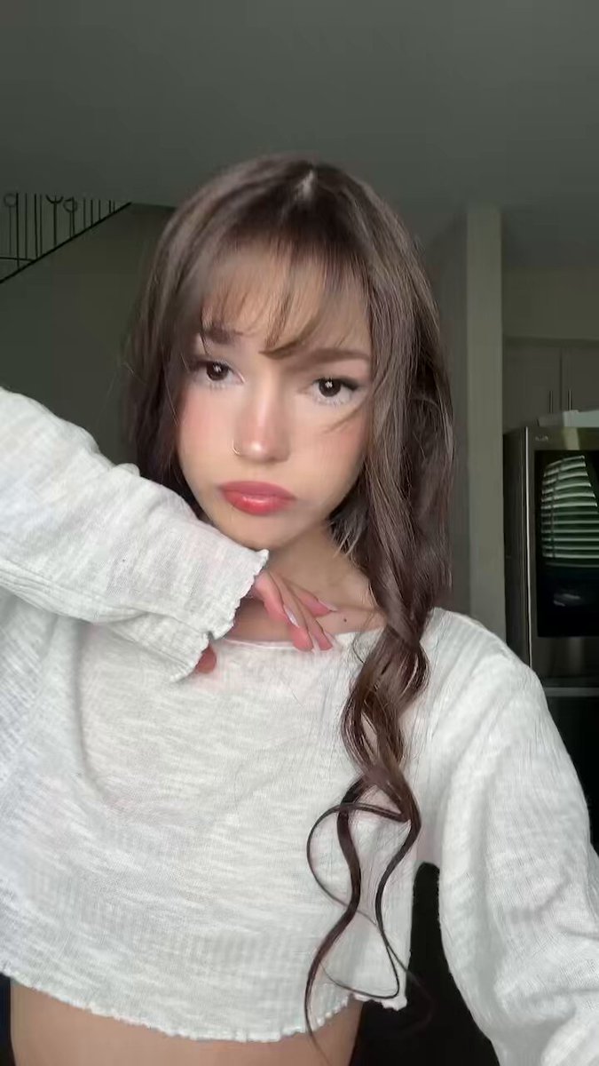 Brunette with bangs in a white long-sleeve crop (@itsjustkatrina_)