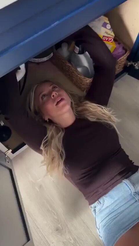 Blonde in a brown long-sleeve and denim shorts stuck under a sink (@elpersmosyc)