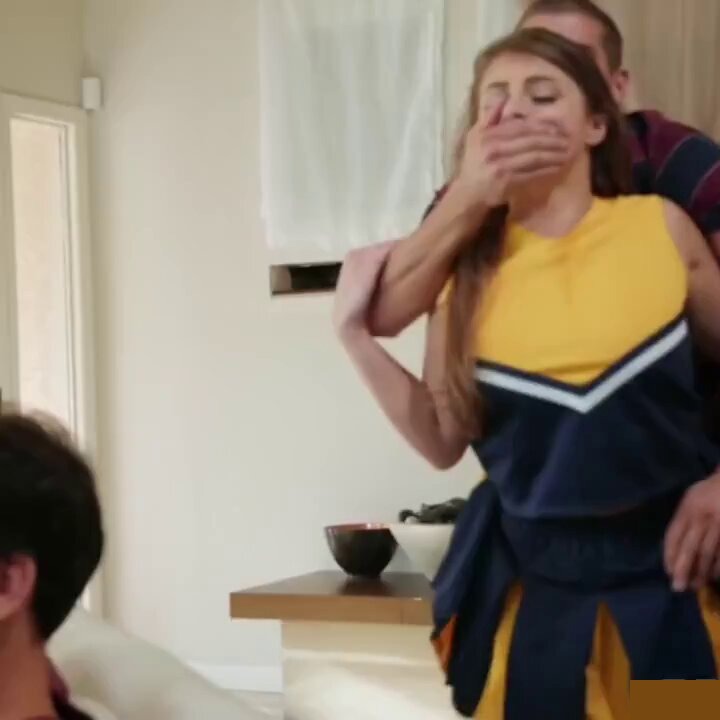 Brunette in a yellow and navy cheerleader outfit with a man covering her mouth (@1publicsex__)