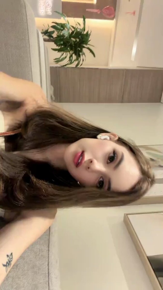 Brunette with an AirPod lying on a beige couch (@Goddess___Nikky)