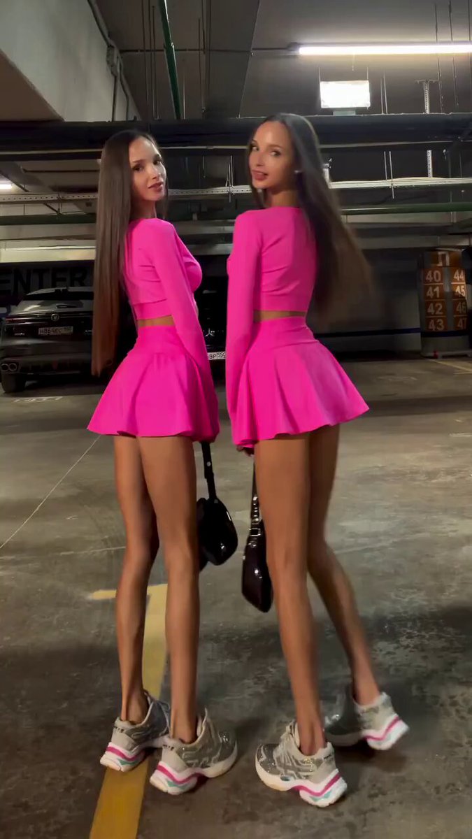 Two brunettes in matching pink crop tops and mini skirts in a parking garage (@julie_marinet)