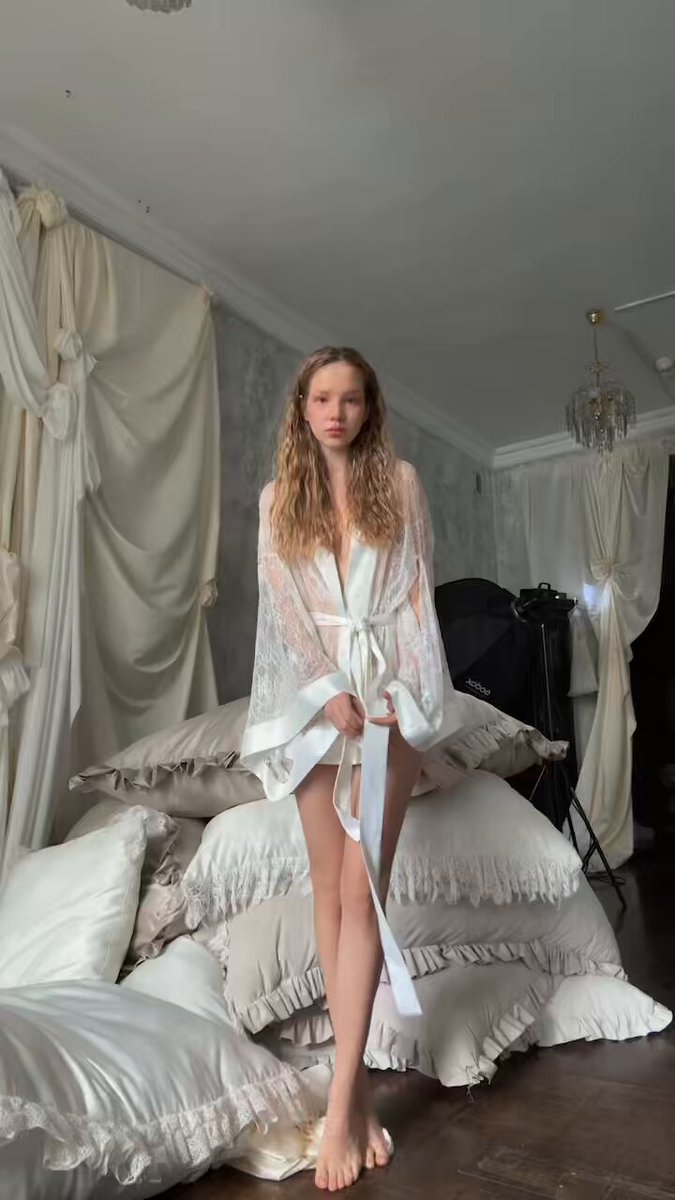 Wavy-haired brunette in a white lace robe on stacked pillows (@CutieLesya)