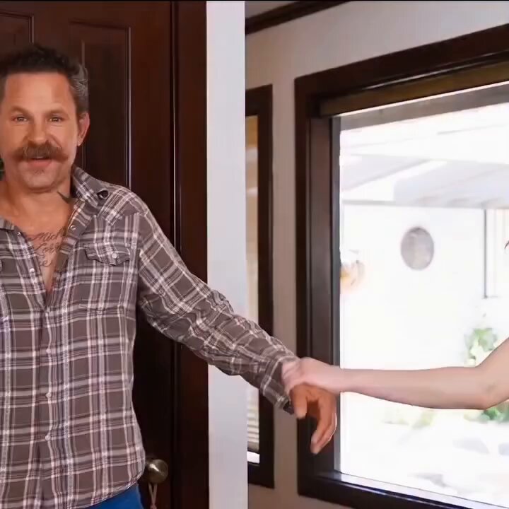 Mustached man in a plaid shirt at a door holding a woman's hand (@xun1989)