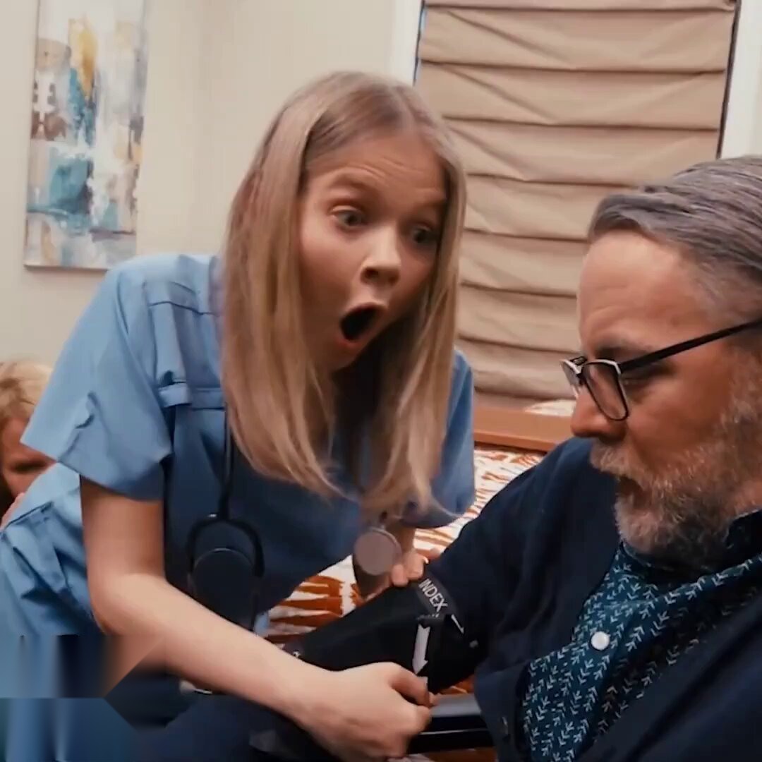 Blonde in blue scrubs taking an older man's blood pressure
