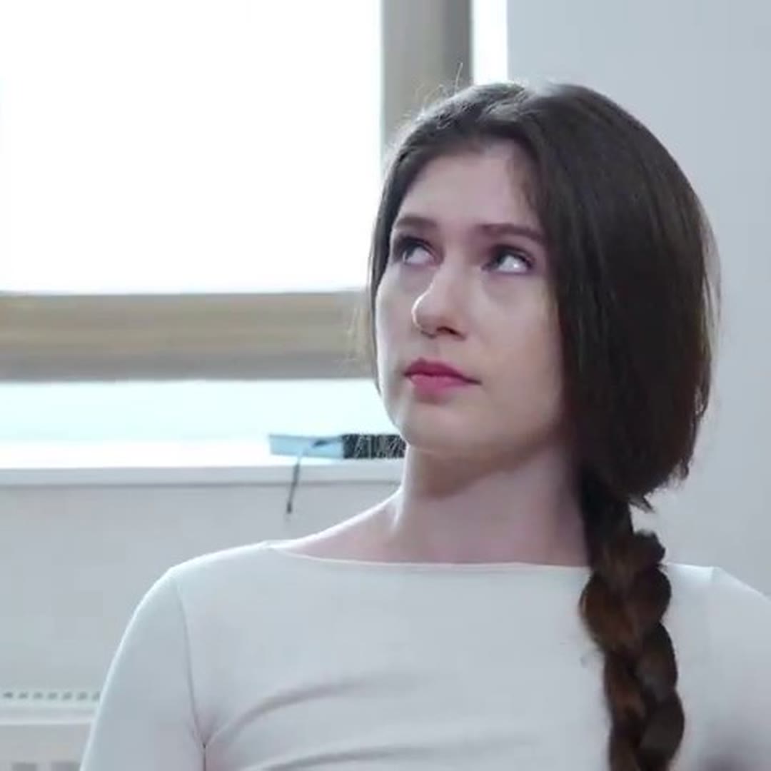Brunette with a braid in a white long-sleeve looking aside