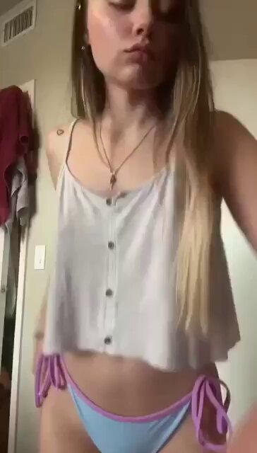 Blonde in a white button camisole and blue bikini bottoms with purple ties