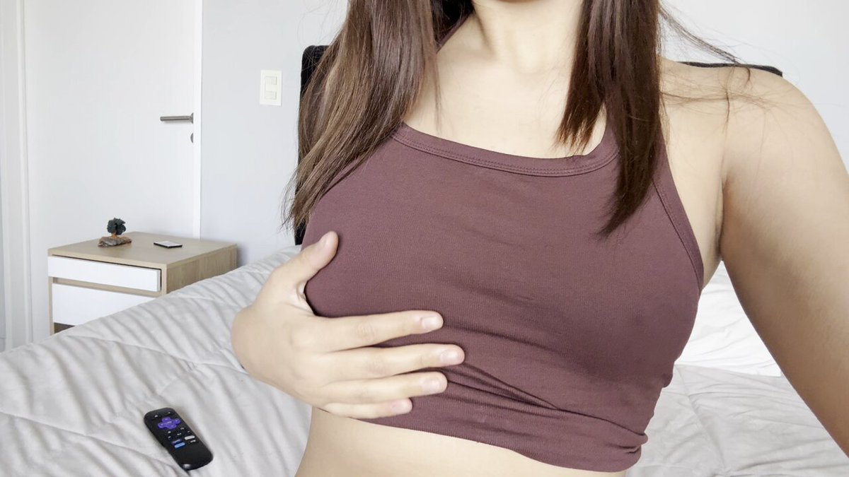 Brunette in a mauve racerback crop top on a white bed