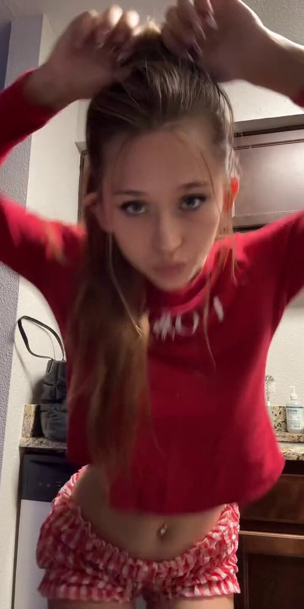 Brunette in a red crop top and red-and-white gingham shorts in a kitchen