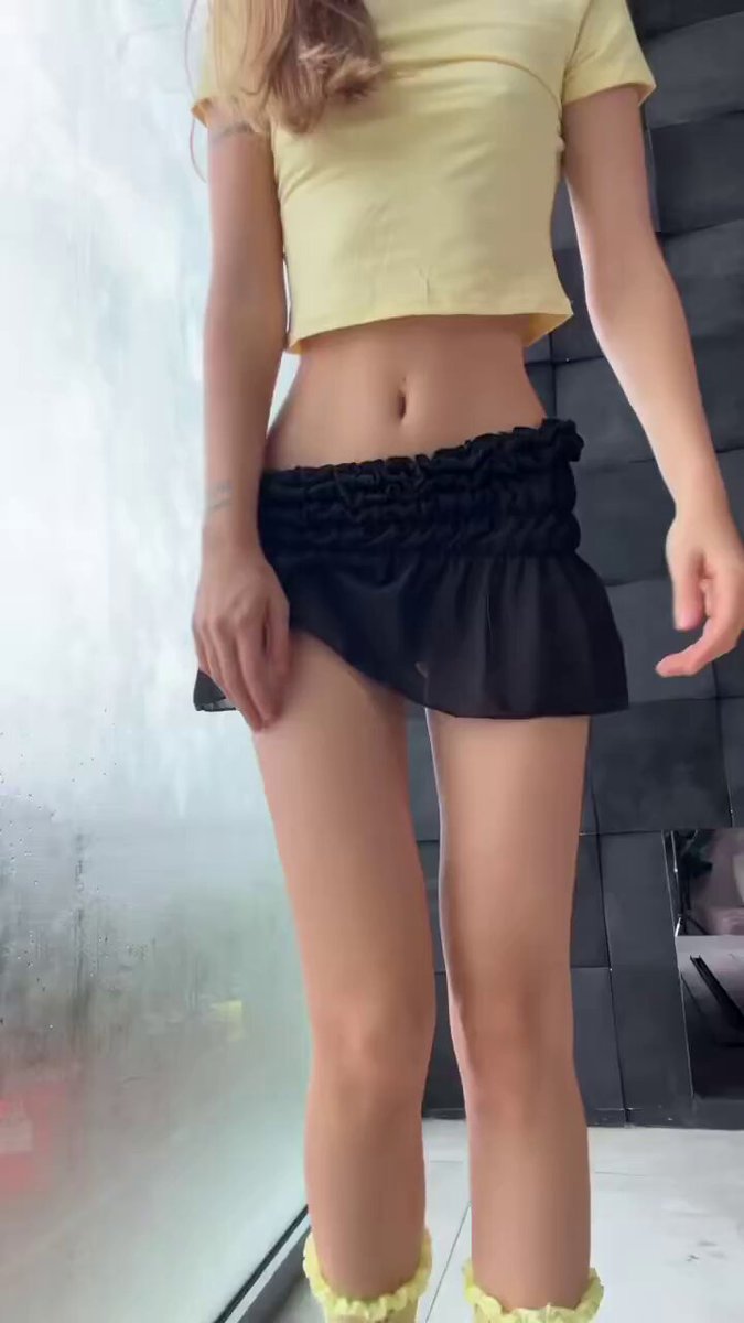 Brunette in a yellow crop top, black ruffled mini skirt, and yellow ruffle socks