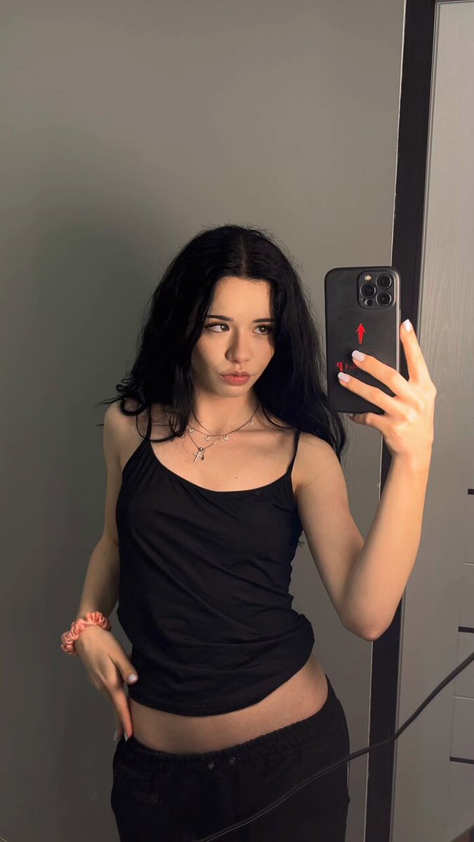 Brunette in a black cami taking a mirror selfie