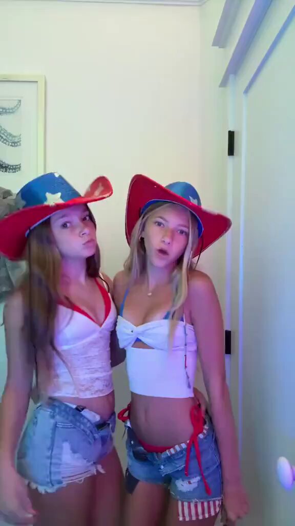 Brunette and blonde in cowboy hats, white crop tops, and denim shorts