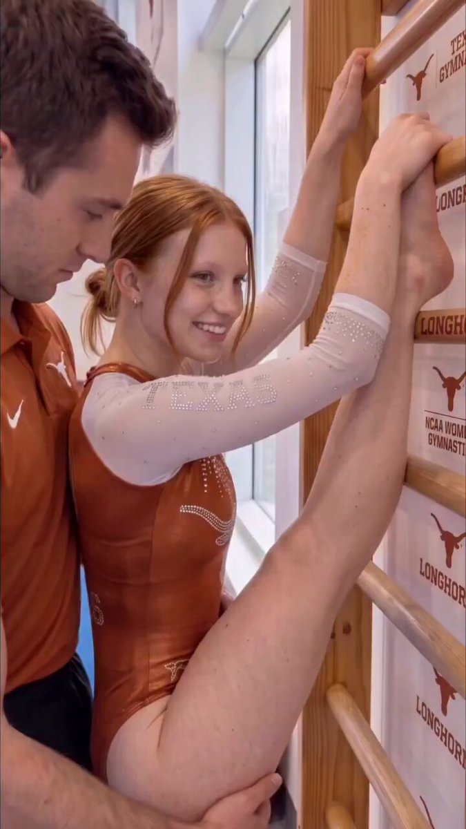Redhead in an orange Texas leotard doing a split on wall bars